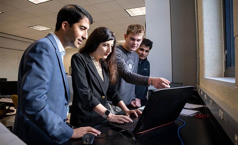 Associate Professor Mojtaba Vaezi works with students at a computer.