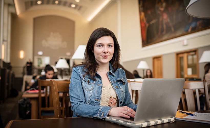 Graduate student working on her laptop in the library