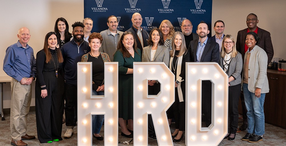 image of faculty standing behind large HRD display