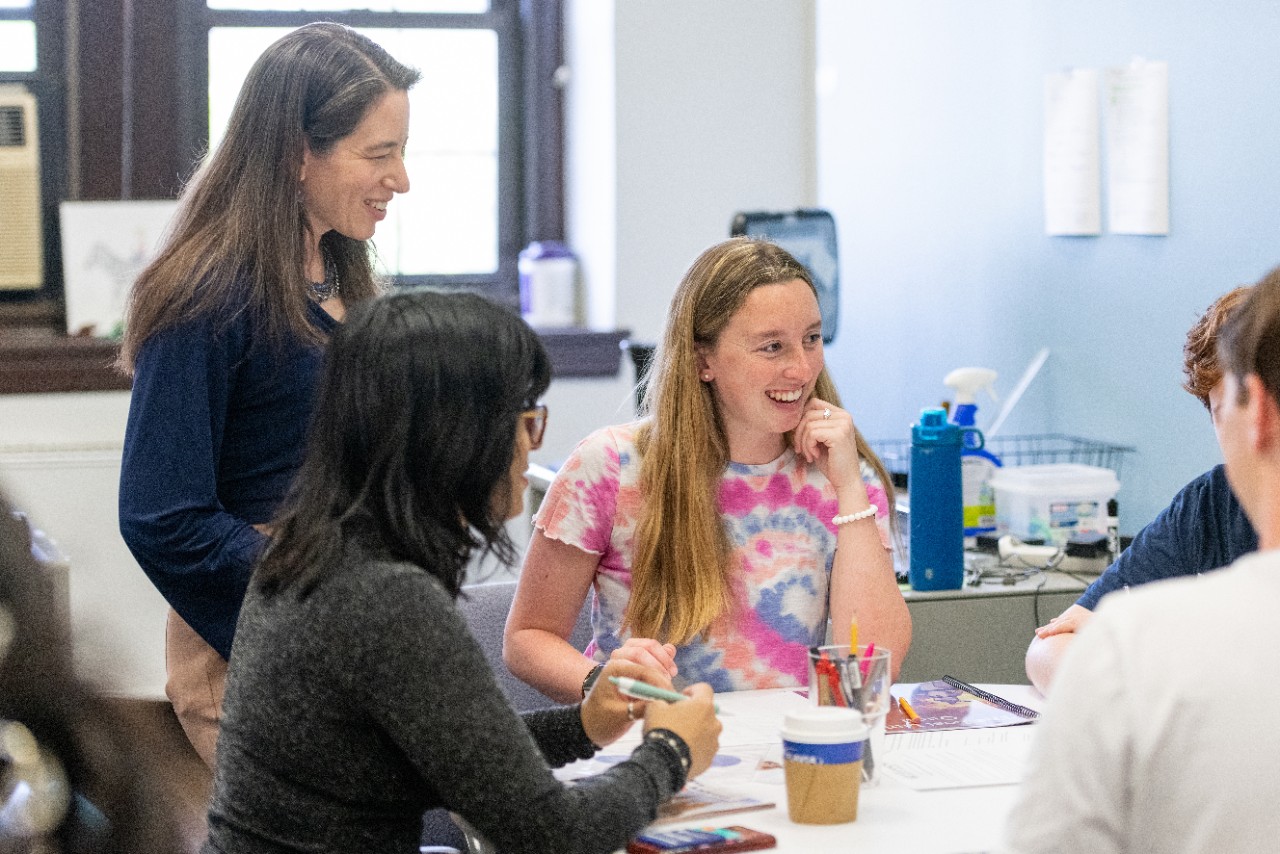 Dr. Weisberg, standing, oversees a group discussion at a table