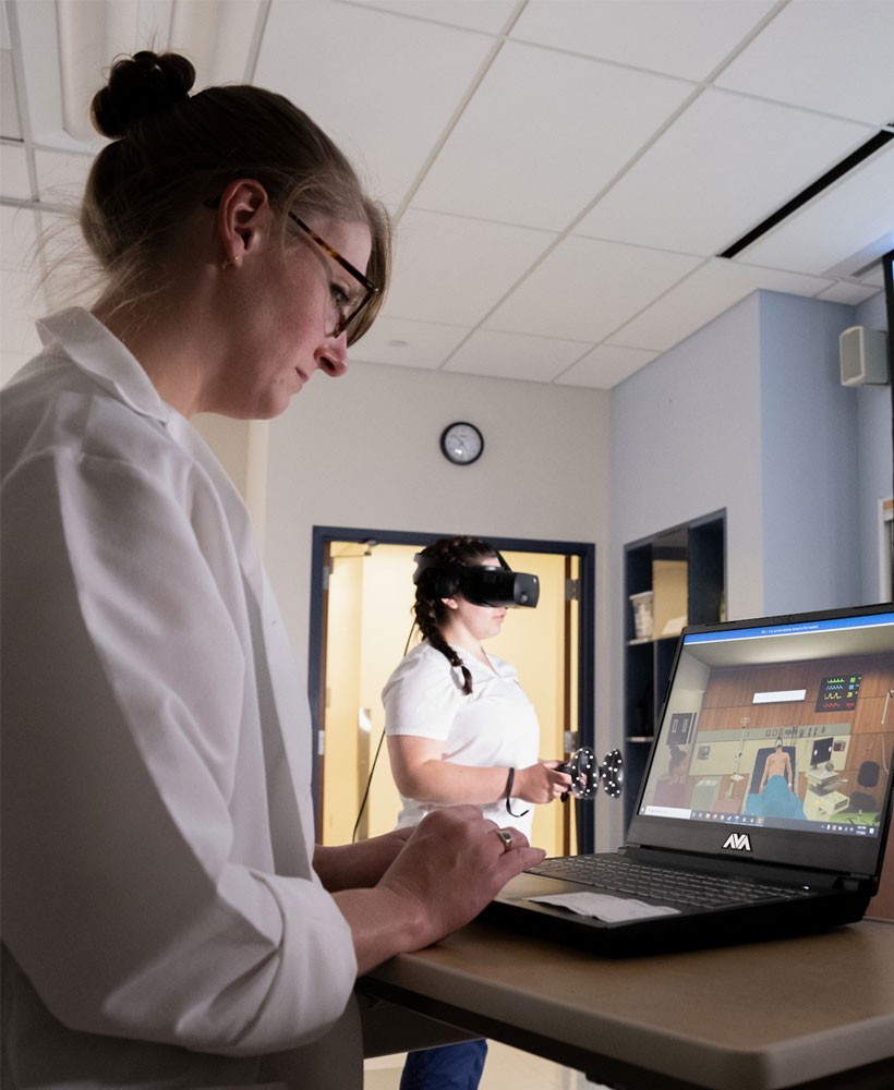 Female professor viewing laptop in virtual reality lab