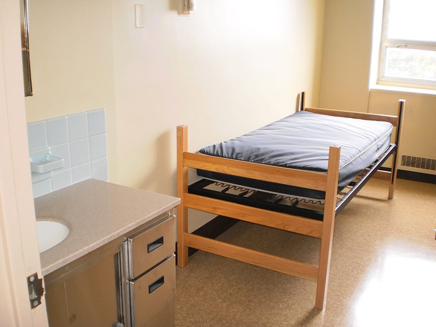View of a bed and sink and vanity in a St. Mary's Hall single room.
