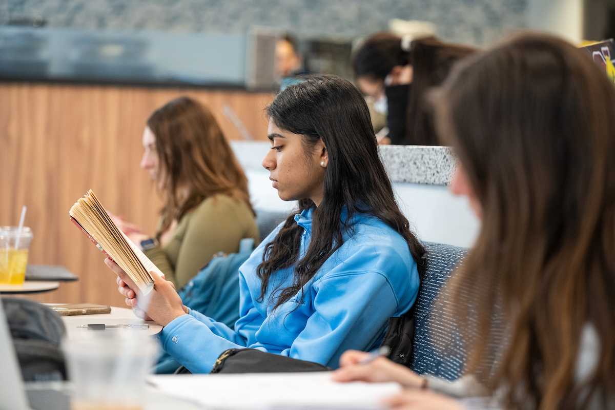 Female student reading at a table.