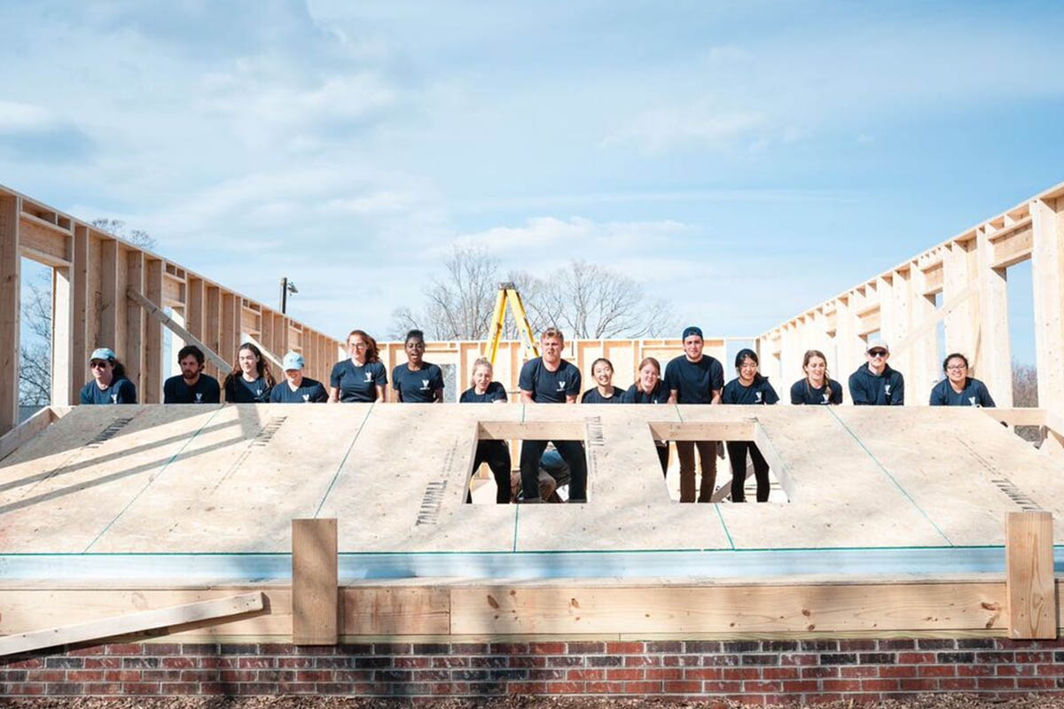 Students putting up the walls of a house