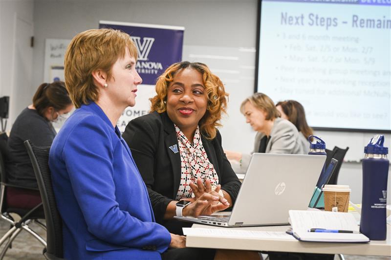 Two women sitting in front of laptop in class