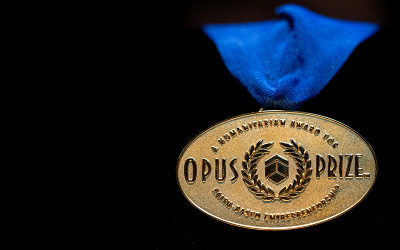 The gold Opus Prize medal hangs on a blue ribbon